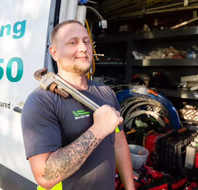 A man holding a wrench in front of a truck.