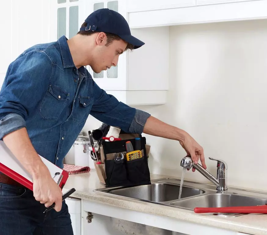 A man is fixing the faucet of his kitchen sink.