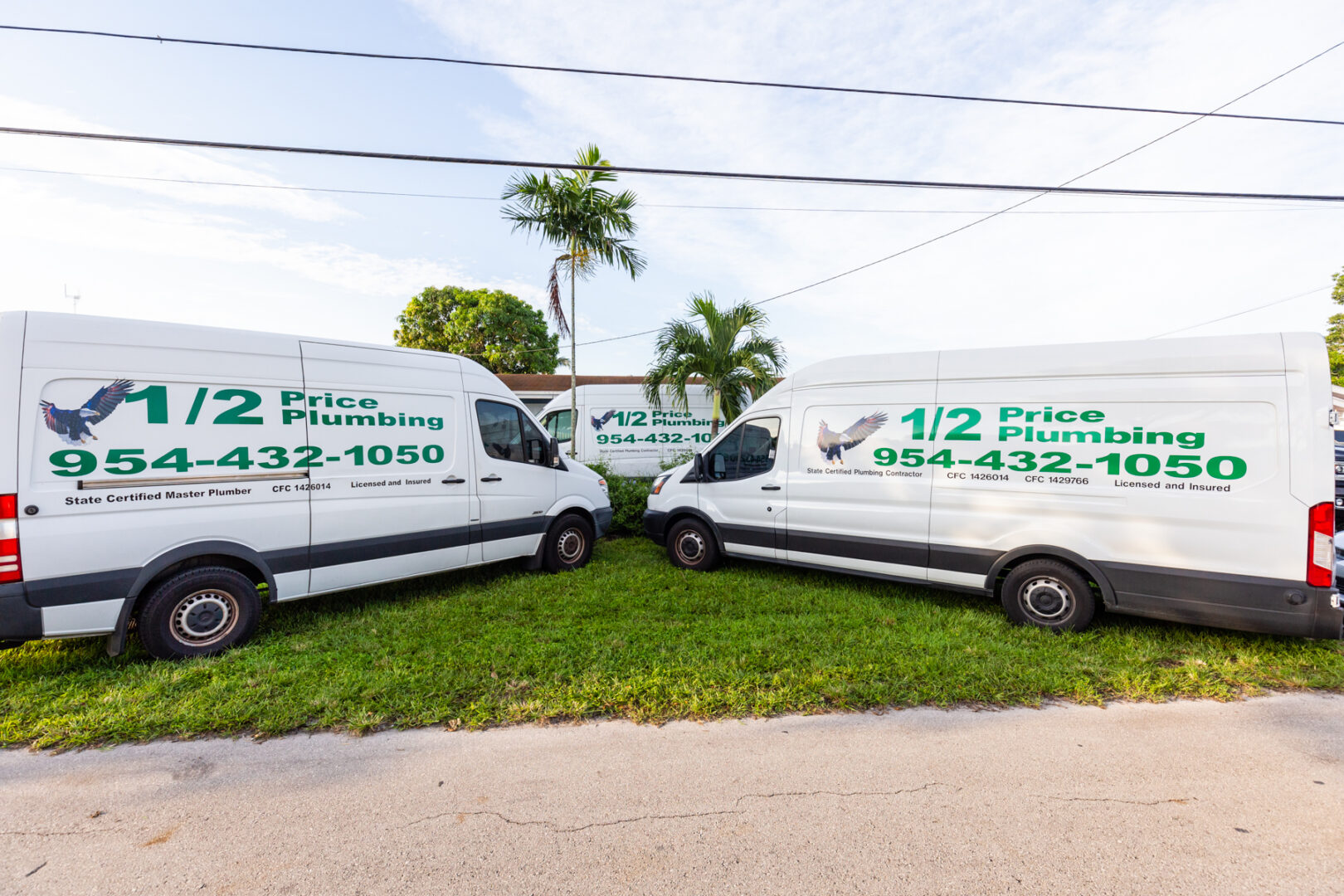 Two white vans parked in a lot on grass.