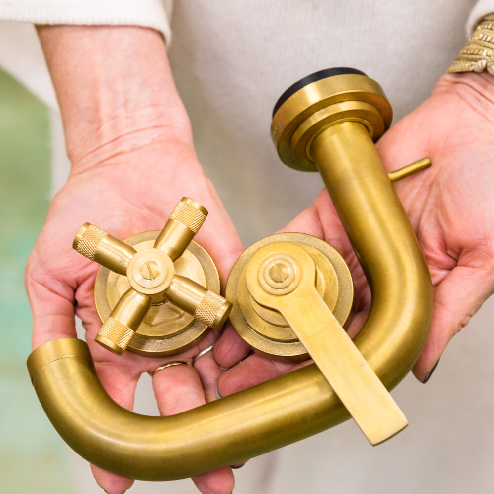 A person holding two brass pipes in their hands.